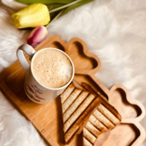 Enjoy a cozy breakfast setup with coffee and toast on a wooden tray adorned with tulips.